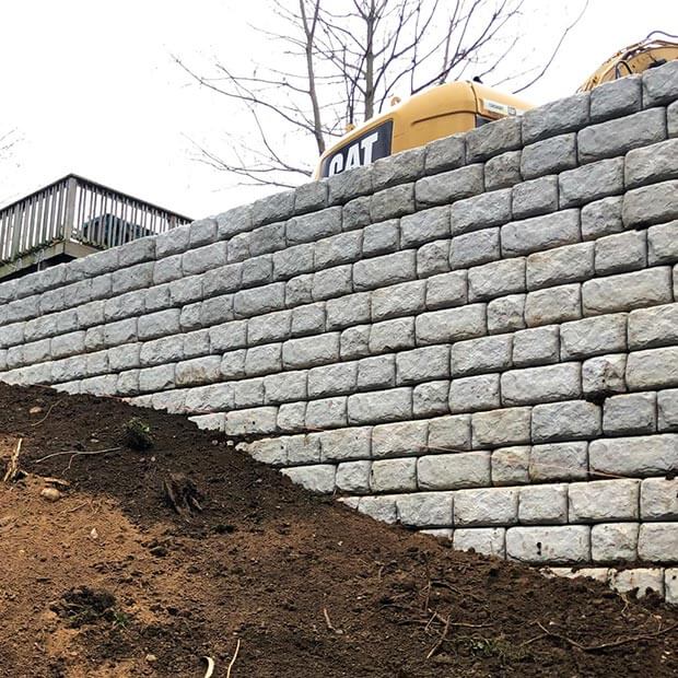 High retaining wall built with white composite stone.